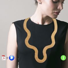 a woman wearing a black top with a gold necklace on it's neck and two green buttons in front of her