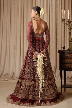 a woman in a red and gold bridal gown standing next to a table with flowers on it