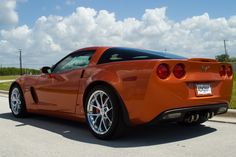 an orange sports car parked on the side of the road