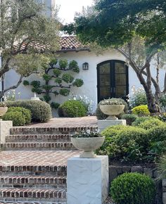 a white house with steps leading up to the front door and trees in the yard