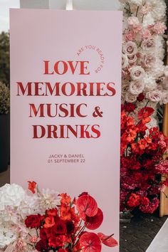 a sign that says love memories, music and drinks next to flowers on the ground