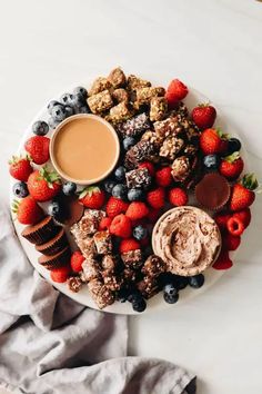 a white plate topped with desserts and fruit next to a cup of chocolate sauce