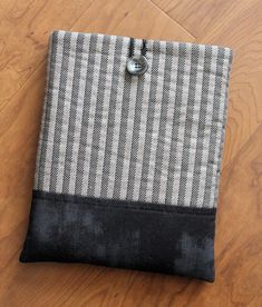 a black and white striped bag sitting on top of a wooden floor next to a button