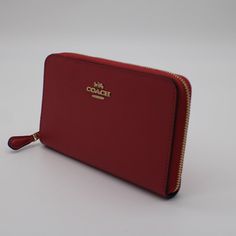 a red zip around purse on a white surface with the name coach written on it