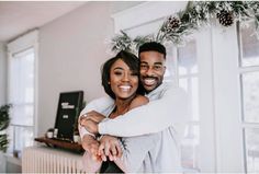 a man and woman hugging each other in front of a christmas wreath on the wall