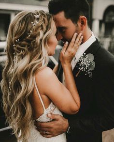 a bride and groom embracing each other in front of a black car at their wedding