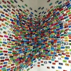 a room filled with lots of different colored cars on the wall next to a toilet