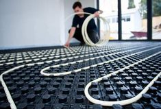 a man kneeling down on the floor with two hoses in front of him