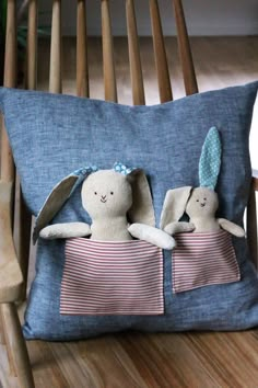 two stuffed animals are laying on a pillow in the shape of a bunny and an elephant