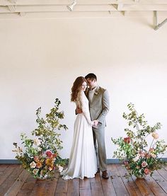 a bride and groom standing next to each other in front of flowers on the floor