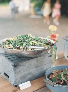 a wooden table topped with lots of food and bowls filled with vegetables on top of it