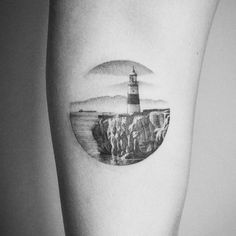 a black and white photo of a lighthouse on the side of a woman's leg