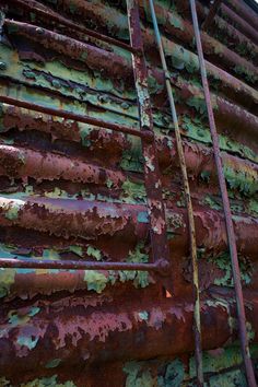 an old rusted metal structure with green and red paint on it's sides