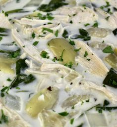 a close up view of some food in a white sauce with green garnish