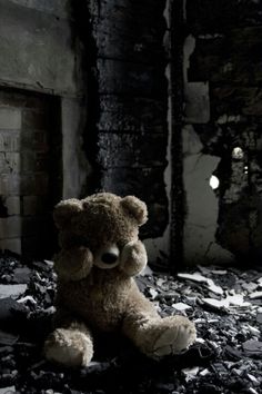 a teddy bear sitting in the middle of a room filled with rubble and broken windows