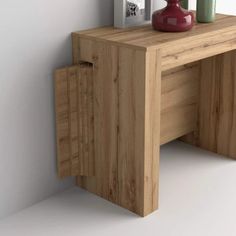 a wooden table with two vases on top of it next to a white wall