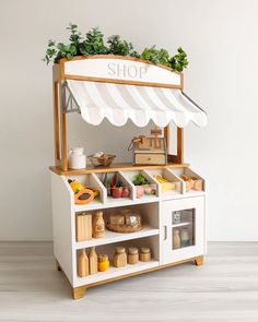 a toy food cart with an awning over it's top and various items on the shelves