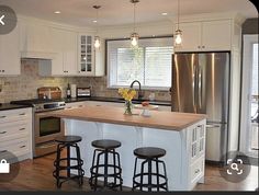 a kitchen with three stools and an island in the middle, surrounded by white cabinets