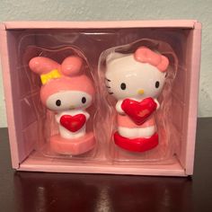 two hello kitty figurines are in a pink box