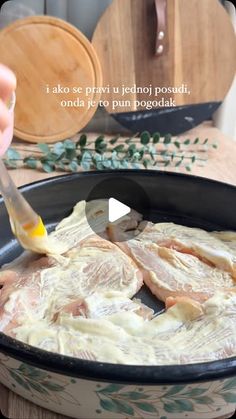 someone is spreading sauce on some meat in a pan