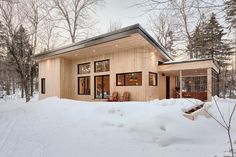 a house in the snow with lots of windows and wood trimmings on it