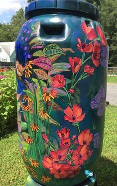 an artisticly painted urn sits on the grass in front of some flowers and butterflies