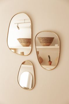 three mirrors hanging on the wall with bowls in them and one is reflecting an empty shelf