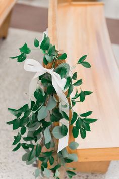 a bunch of green leaves on top of a wooden table next to a white ribbon