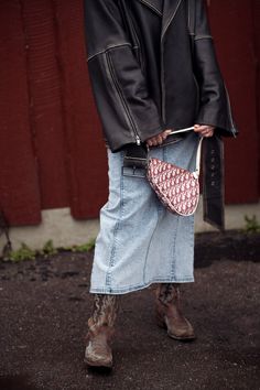 a woman is holding a purse in her hand while standing next to a red wall