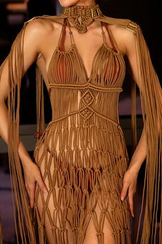 a woman in a brown dress with fringes on her head and chest, posing for the camera