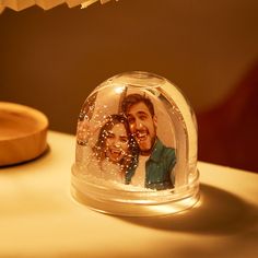 a snow globe with an image of two people in it on a table next to a lamp