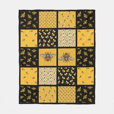 a yellow and black patchwork quilt with bees on the front, in squares that appear to be made out of honeycombs