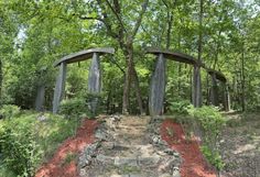 an outdoor sculpture in the middle of a forest with trees and rocks on it's sides