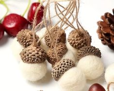 several different types of wool balls and pine cones on a white surface with cherries in the background