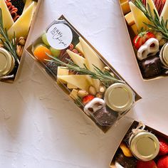 three boxes filled with different types of cheeses and fruit on top of each other