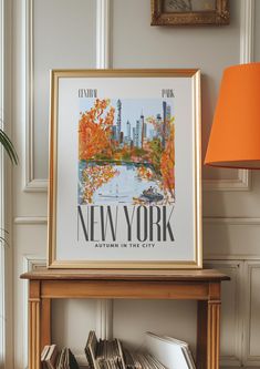 a framed new york poster sitting on top of a book shelf next to a lamp