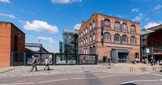 people are walking on the street in front of an old brick building with glass doors