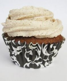 a cupcake with white frosting on top sitting in a black and white wrapper