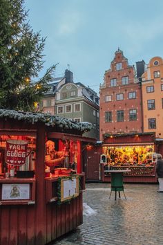 an outdoor christmas market in the middle of a city street with buildings and lights on it