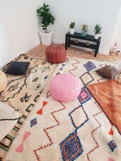 a living room area with rugs, pillows and potted plants on the floor