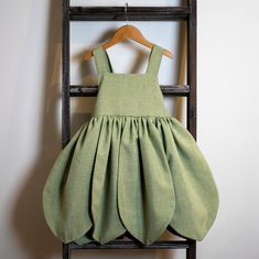 a green dress hanging on a clothes rack with a wooden hanger in front of it