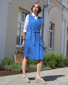 Our trench linen dress LISBON in Cobalt blue marries professional flair with sustainable style. Sleeveless and inspired by the iconic trench coat, it boasts a double-breasted button closure and a sleek tie belt for a defined silhouette. Versatile enough to be worn as a dress or a long vest over a white shirt and jeans, it features eco-friendly Bioresin buttons and side pockets, ensuring a polished, environmentally-conscious look. Details: * Straight cut * Midi-length * Side pockets  * Sleeveless * V-neck with lapels * Double-breasted button closure and tie belt * Features front flaps and a closed slit at the back center * Buttons made from sustainable Bioresin * Trench coat inspired for an official look * The model is wearing size S and is 5'11" (180 cm) tall. Model measurements: Bust: 34" Blue Belted Button-up Denim Dress, Knee-length Denim Dress With Button Closure, Relaxed Fit, Blue Linen Button-up Dresses, Knee-length Linen Shirt Dress With Button Closure, V-neck Denim Dress With Button Closure, Midi Dress With Pockets, Sleeveless Trench, Wrinkled Clothes, Trench Dress