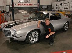 a man kneeling next to a silver car in a garage