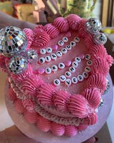 a pink cake decorated with disco balls and words on the top is being held by a person