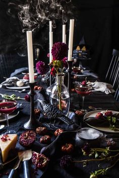 the table is set with candles, plates and other items for halloween dinnereons