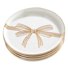 four white and gold plates stacked on top of each other with a bow at the center