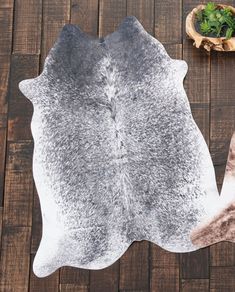 a cowhide rug on a wooden floor next to a potted broccoli