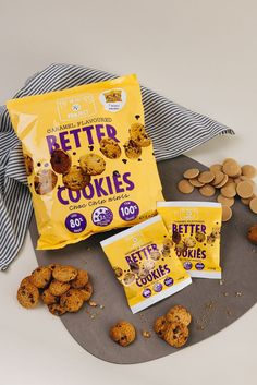 three bags of better cookies sitting on top of a plate next to some cookies and chips