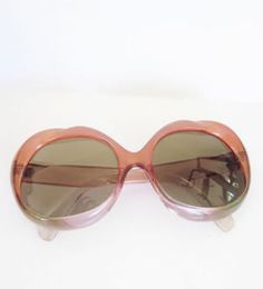 Large, round sunglasses in a translucent purple/pink color. Made in Italy. Case included  Label: -- Decade: 1970s/1980s Condition: Excellent Materials: Plastic Marked Size: -- True Size: -- Measurements: 6 inches wide 2.5 inches long  More photos here: http://totalrecallvintage.com/pink_lady.html Retro Pink Sunglasses For Spring, Retro Purple Sunglasses With Tinted Lenses, Retro Purple Sunglasses With Gradient Lenses, Vintage Purple Sunglasses With Tinted Lenses, Retro Pink Sunglasses With Gradient Lenses, Retro Pink Sunglasses With Mirrored Lenses, Vintage Pink Sunglasses For Party, Vintage Pink Sunglasses For Summer, Retro Pink Plastic Sunglasses