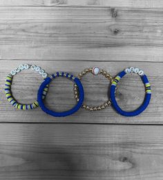 three bracelets are hanging on a wooden wall, one is blue and the other is yellow